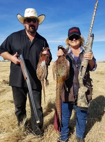 A couple showing off their pheasant hunt